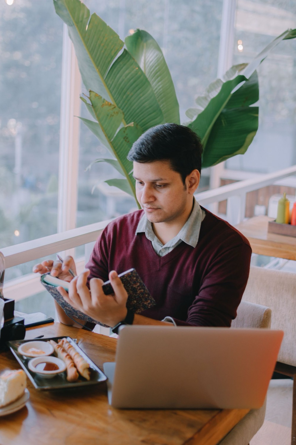 Restaurant owner checking his phone at a table beside a laptop