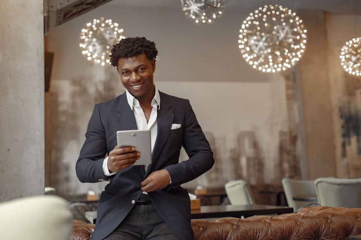 Smiling restaurant owner checking his tablet in the dining room
