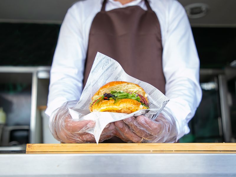 Cook handing a wrapped burger across a food truck counter
